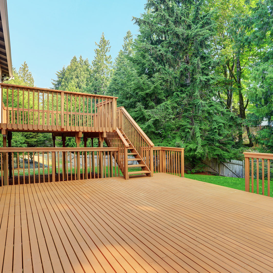 Backyard View Of Grey Rambler House With Upper And Lower Decks Decks